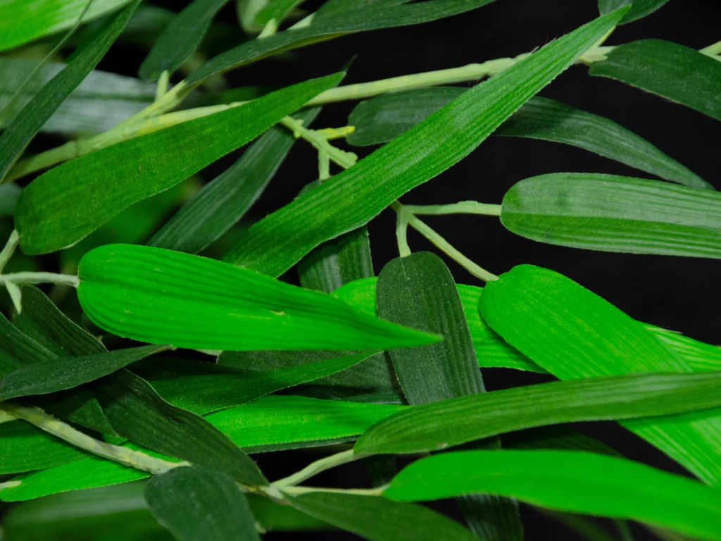 Close-up of artificial bamboo foliage with overlapping slender green leaves and visible parallel veins.