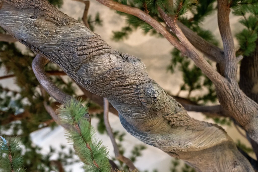 Close-up of artificial Ancient Bristlecone Pine tree branch showing textured bark detail and green needle foliage.